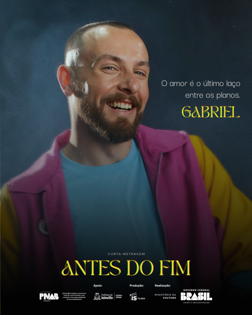 Cartaz do curta-metragem Antes do Fim. No centro, o personagem Gabriel sorri levemente, vestindo uma jaqueta rosa com detalhes amarelos e uma camiseta azul-clara, sob uma luz suave que destaca seu rosto e expressão serena. Ao lado dele, lê-se a frase: “O amor é o último laço entre os planos.” Abaixo, o título Antes do Fim aparece em letras amarelas, seguido pelos créditos de produção e apoio institucional: Política Nacional Aldir Blanc, Prefeitura de Joinville, Secretaria de Cultura e Turismo, produção da IS Filmes e realização do Governo Federal e Ministério da Cultura.